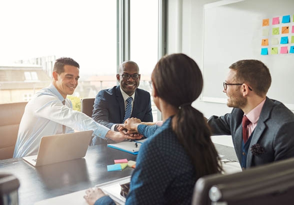 Staff members having a board meeting touching hands like a team