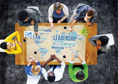 A group of people around a square table working on a leadership board